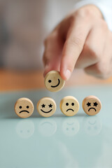 Selecting a happy mood: Hand picking smiling face block among other negative emotions. Represents positive feedback and mental health.