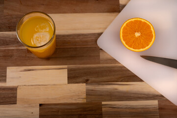Naklejka premium Refreshing orange juice and halved orange on wooden table