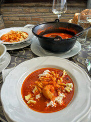 Delicious red fish stew with shrimp and handmade pasta, served in a rustic setting with bread and white wine, capturing the essence of traditional cuisine.