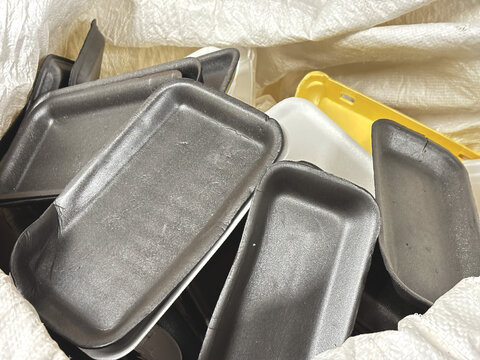 Used foamed polystyrene waste collected in a bag for recycling, styrofoam padding for product packaging, disposable foam food containers.