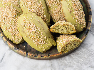 Matcha madeleine cookies with white chocolate frosting on marble background
