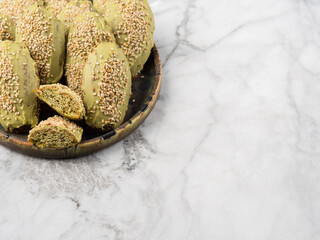 Matcha madeleine cookies with white chocolate frosting on marble background