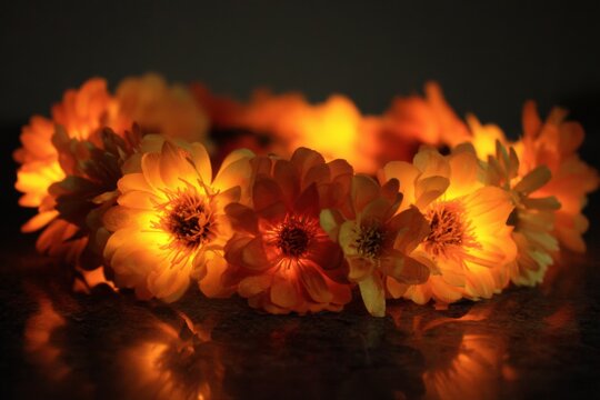 Marigold flower crown with internal lights placed on dark surface for Day of the Dead accessory documentation
