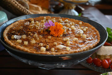 gourmet quiche or savory tarte decorated with edible flowers, brunch table food display, elegant party starter, tropaeolum majus, close-up of delicious pastry

