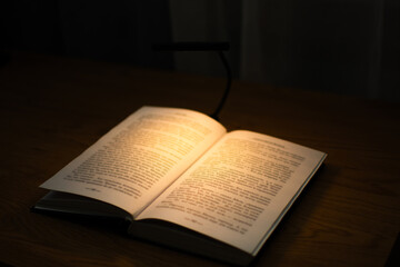 Fototapeta premium A convenient clip-on reading lamp with color options, placed over a book on the table for reading
