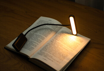 Fototapeta premium A convenient clip-on reading lamp with color options, placed over a book on the table for reading