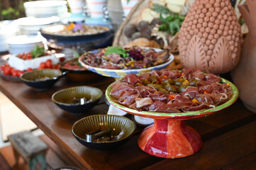gourmet charcuterie platter close up, prosciutto ham and pickled vegetables antipasto, luxurious fine dining buffet setup, decorated table centerpiece and food

