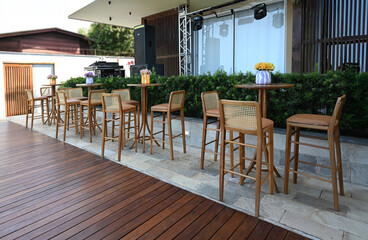 outdoor cafe in the city, modern outdoor bar seating, wooden high chairs with tables, elegant patio setup for events, cozy social gathering area