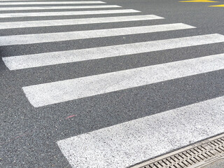 Urban crosswalk on asphalt road with drain cover in daylight