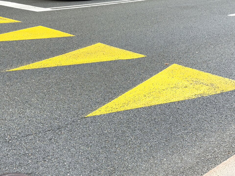 Traffic safety: asphalt road with yellow triangular arrow markings