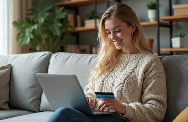 Smiling young lady shops online at home. Woman uses laptop, holds credit card, buys online. Female makes purchase easy with e-commerce, stays relaxed on sofa. Online banking.