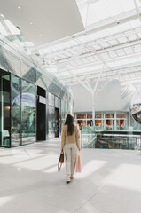 Girl from the back with shopping bags walking in the mall.