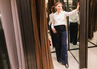 A girl in a new outfit is standing in the fitting room of a store.