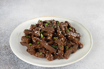 Stir-fried teriyaki beef with sesame seeds on a gray background. Asian cuisine.