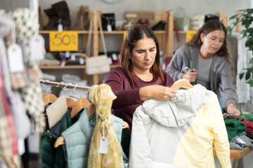 Fototapeta premium Adult woman buyer choosing down coat in clothing store
