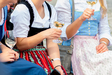 Women in traditional dress holding glasses of white wine at a festival.