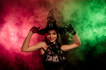 Glamorous woman posing in witch costume with colorful mist, perfect for Halloween holiday and festive celebrations