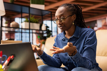 Young remote worker smiling during a virtual meeting with her trainer, showcasing the productivity of online tools and networking. Black woman starting her training session for the new job.