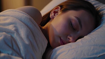 A serene close-up video angle of a young woman peacefully sleeping, wrapped in a white blanket, capturing a calm and restful ambiance.