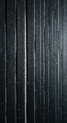 A close-up view of dark vertical wooden planks covered in glistening white frost, with tiny snowflakes gently falling in a cold, atmospheric winter scene.