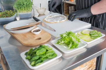 The chef prepares a flatbread with herbs. 