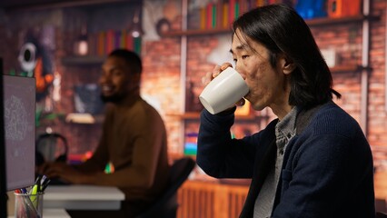 AI startup office chief technology officer drinking coffee and building application. Senior manager enjoying hot beverage while working in artificial intelligence software development agency, camera B
