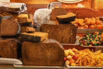 Large slices of traditional fruitcake displayed with candied fruits at Christmas holiday market. Concept of bakery sweetness, fruitcake tradition, festive dessert