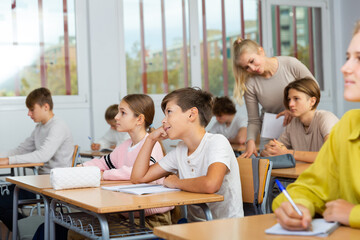 Group of teenage girls and boys exercising during lesson in classroom.