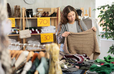 Fashionista girl near showcase examine goods, knitted scarf. Off line clothing store from retailer. Style and fashion type look, modern trends. Outlet, discount store