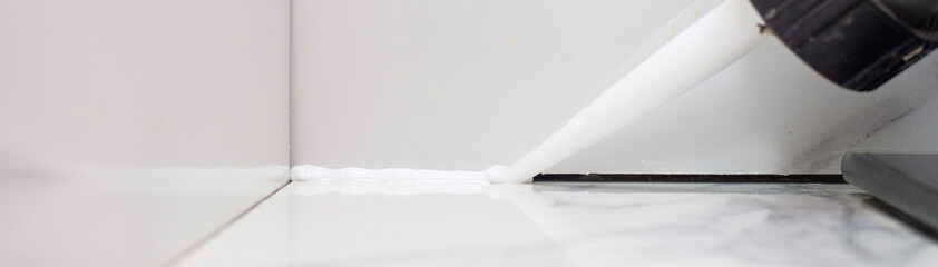 applying sealant to the gap between porcelain tiles to prevent debris from getting in and unsanitary conditions