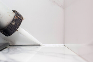 applying sealant to the gap between porcelain tiles to prevent debris from getting in and unsanitary conditions