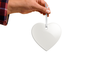 Hand holding Christmas heart ceramic ornament or decoration with golden string mockup isolated on a transparent background, PNG. High resolution. Mockup, template ready for your design.