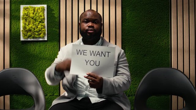 Black HR professional from the department showcasing advertisement banner promoting a job opening within the company, confidence in talent recruitment. Available vacancy position. Camera A.
