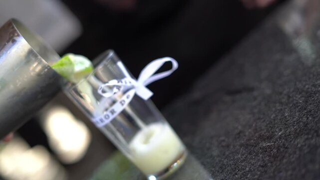 waiter serving caipirinha, a Brazilian cocktail, in a glass with a bonfim ribbon