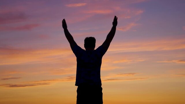Sports, man warms up, trains his body, raising his arms outdoors, warming up for outdoor fitness. Healthy lifestyle. Breathing exercises outdoors, arm swings in park in morning, evening, training, sky