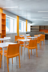Bright and cheerful interior of a modern café with orange chairs and clean lines