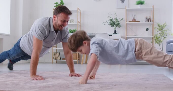 Sporty family fun, father and small son in casual clothes doing pushup pressup exercise on carpet in living room for healthy lifestyle, getting physically stronger, have fun, weekend pastime with kid 