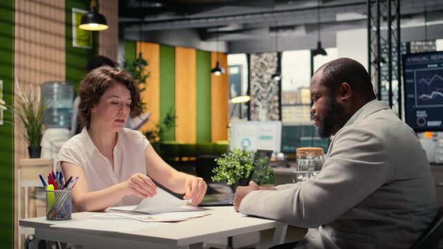 HR professional handing over the paper with job benefits package for candidate to review, checking contract details. Company offering retirement plans and wellness programs. Camera A.
