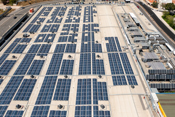 Aerial drone shot showcasing large array of solar panels installed on rooftop of commercial building, contributing to sustainable energy generation and eco friendly practices
