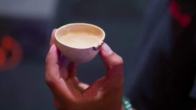 Hand holding jicara with mezcal at a mexican festival