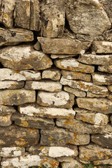 Dry stone wall texture with various natural stones creating a rustic rustic background, showing weathered surface and lichen growth