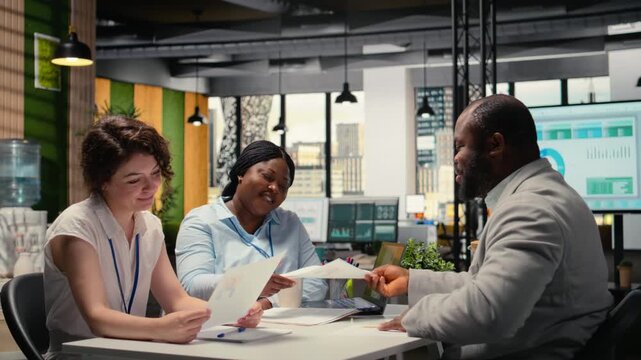Recruiting team and an applicant engaging in CV evaluation in a business office, discussion about career experience and aspirations for growth. Interview process for professional workforce. Camera A.