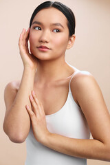 Naklejka premium asian woman is photographed in a clean studio setting, gazing softly to the side with a calm, confident expression, suggesting modern poise and a minimal, versatile look for lifestyle or beauty