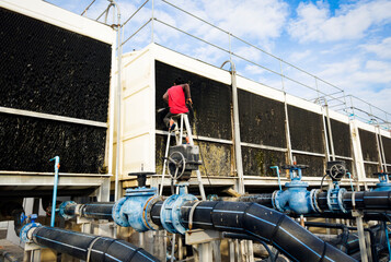 A technician is cleaning an industrial cooling tower without protective clothing.