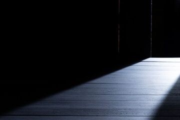 Black wooden floor or empty table with light coming from behind on a black and dark background.