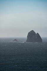 A pair of rocky islands sit steadfast in the Pacific Ocean in the Pacific Northwest, visible from Arch Rock State Park in Brookings, Oregon