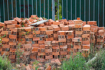 Many red bricks piled neatly outdoors near construction building site