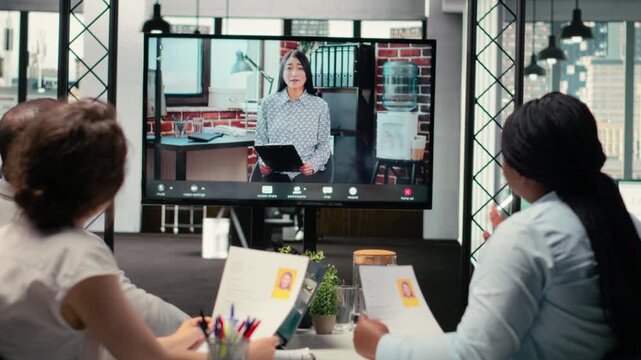Recruiters and applicant engage in a virtual call conversation using webcam and high tech tools, reviewing resume and assessing job search progress during remote interview conference. Camera B.