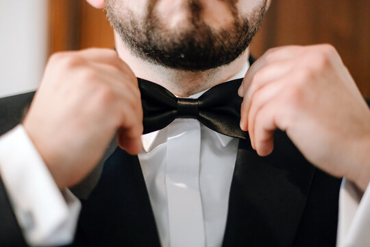Man adjusting bow tie on shirt collar, elegant men’s fashion detail symbolizing wedding style, formal elegance and classic sophistication for ceremony or special event