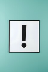 Minimal framed artwork of a bold black exclamation mark on a white background hanging on turquoise wall, representing attention, alert, creativity, design symbol, communication, and modern graphic art